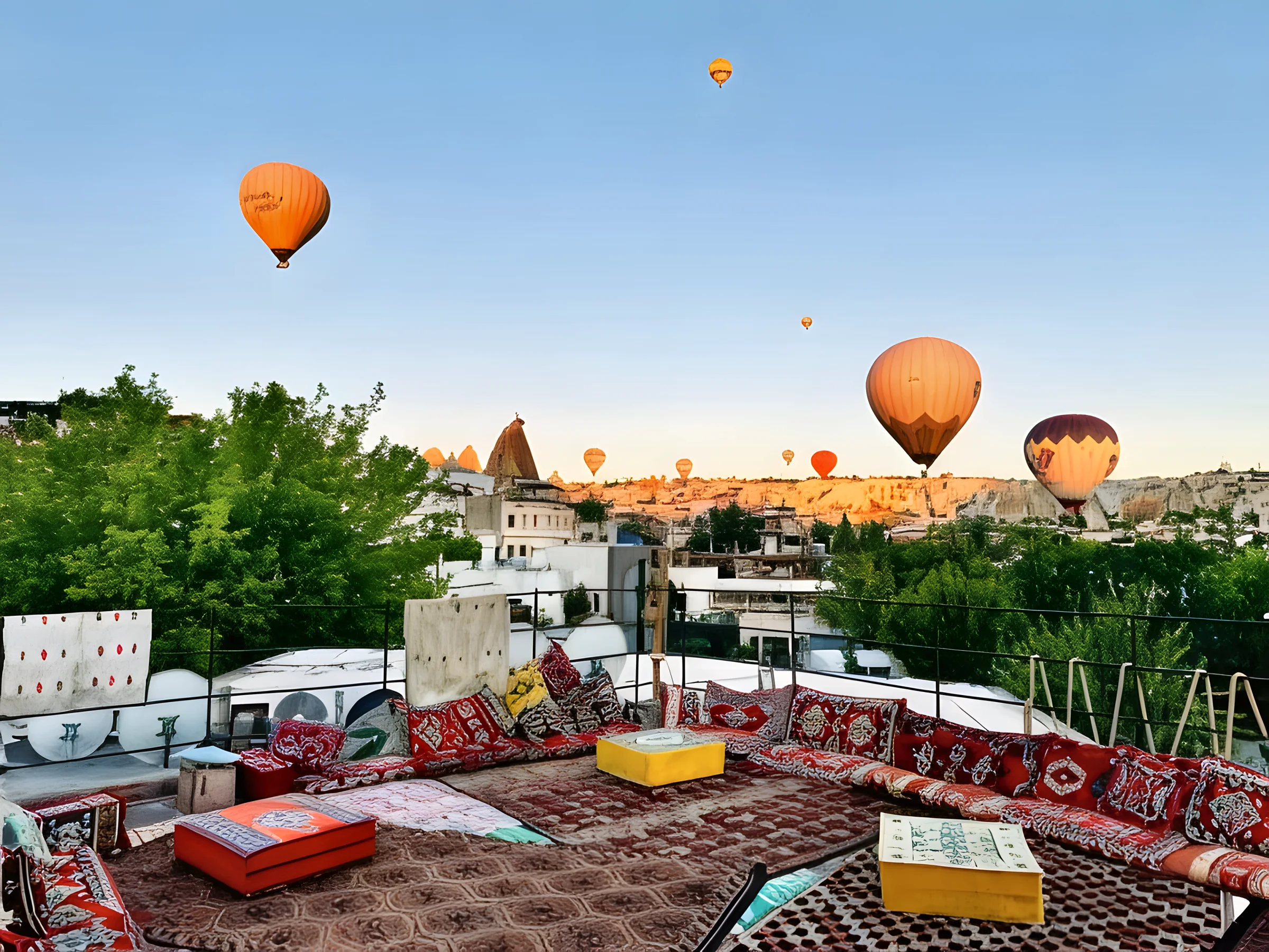 Balloons rising over Göreme at sunrise, seen from the Nomads Cave rooftop